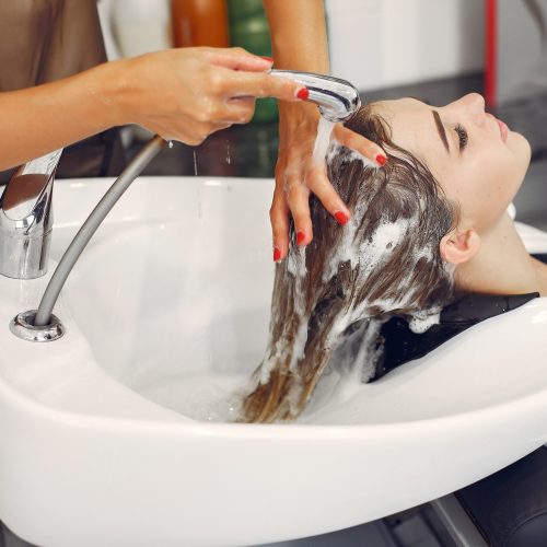 Hairdresser washing head her client. Woman in a hair salon